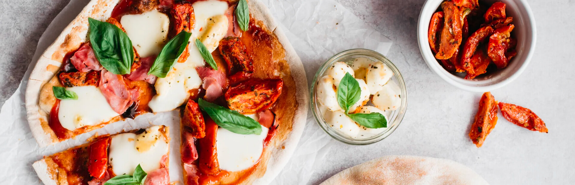 Freshly made barbecued pizza with tomato, ham, basil and mozzarella toppings.