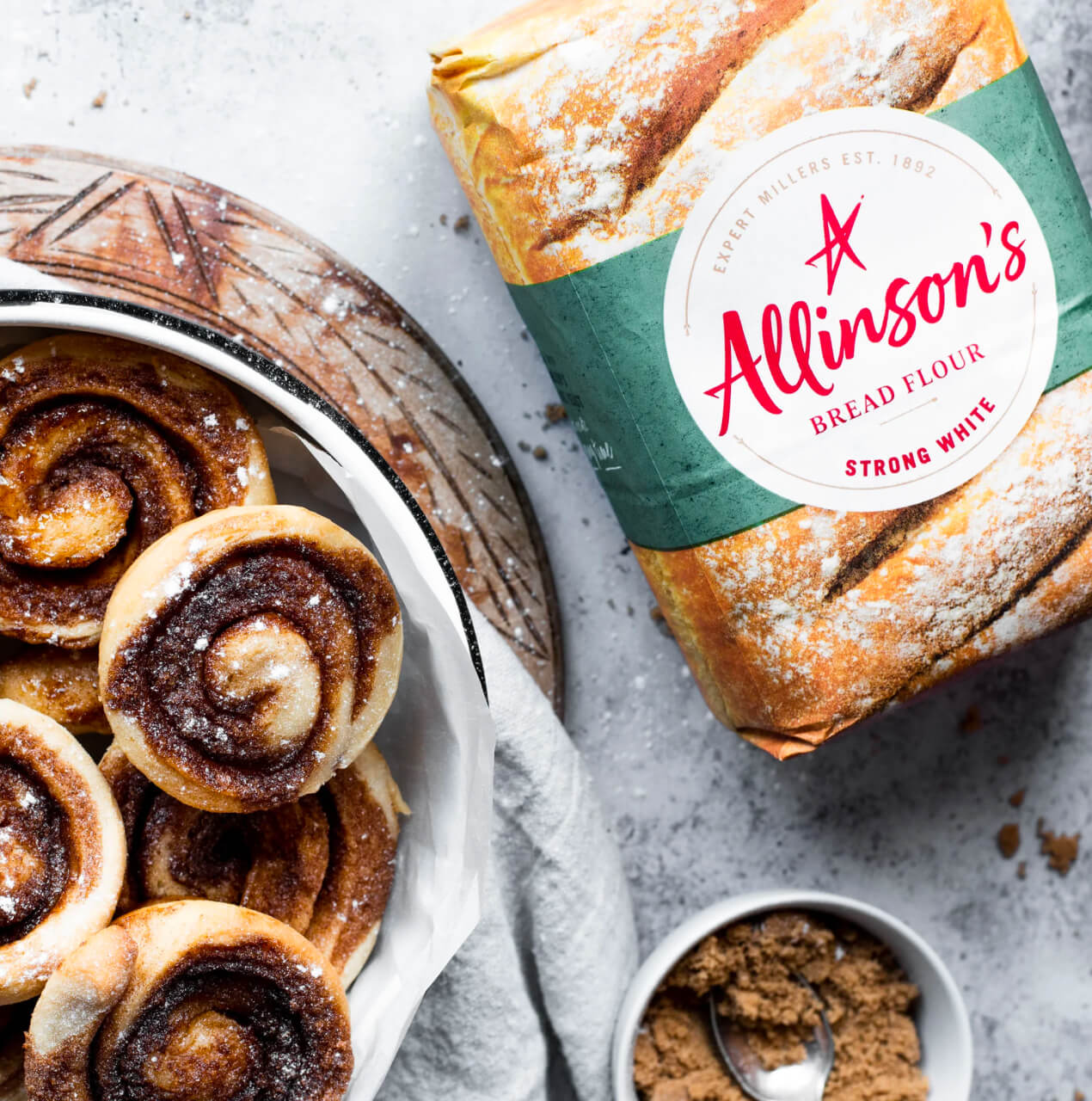 A pack of Allinson's Strong White Bread Flour alongside a plate of home made cinammon rolls.